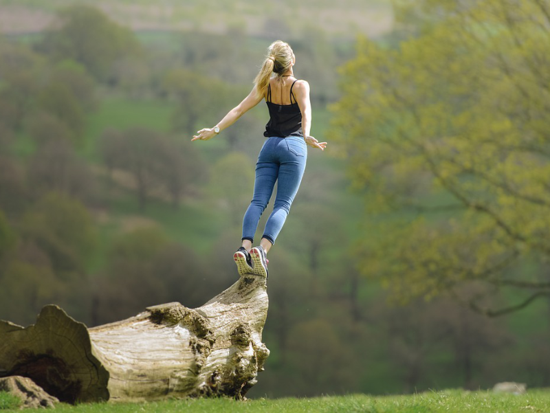 Image of woman standing on fallen tree